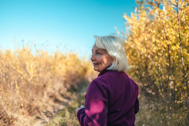 Primer plano de mujer mayor sonriente corriendo en el parque de otoño de la naturaleza. Deportes activos - Foto, imagen