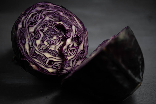 Half red cabbage in dark background. Selective focus on cabbage in blurred background. Close up - Zdjęcie, obraz