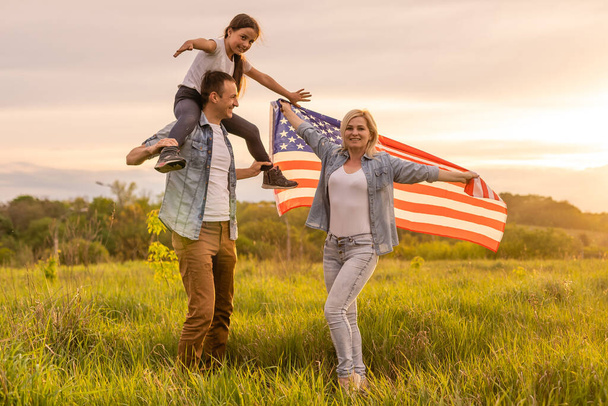 família segurando uma bandeira americana em um campo. - Foto, Imagem