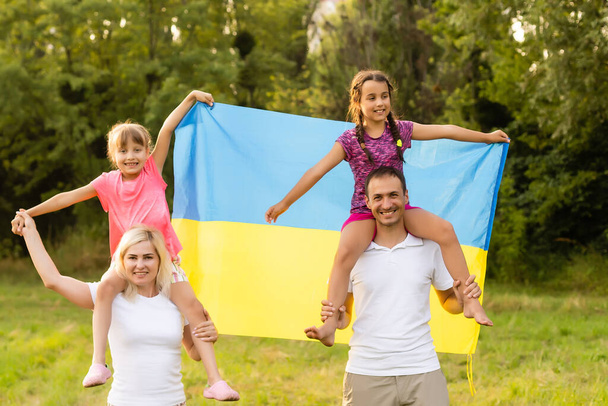 Οικογένεια με τη σημαία του Ουκρανού. Χαρούμενη Ημέρα Ανεξαρτησίας της Ουκρανίας. Ημέρα Εθνικής Σημαίας. Αγάπη για την πατρίδα και σύμβολα. Αντιγραφή χώρου. - Φωτογραφία, εικόνα