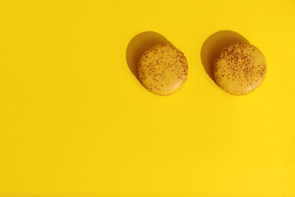 Two Yellow french macaroons on bright yellow background.  Delicious meringue cookies. Food concept - Foto, imagen