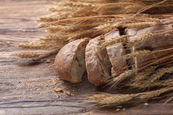 Bread and wheat on wooden table, shallow DOF - Zdjęcie, obraz