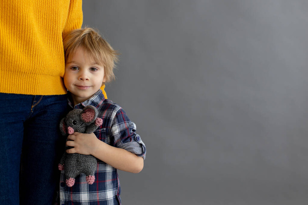 Sad little child, blond boy, hugging his mother at home, holding teddy bear - Photo, Image