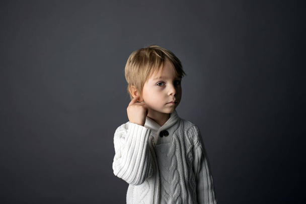 Cute little toddler boy, showing not hearing gesture in sign language on gray background, isolated image, child showing hand sings  - Fotografie, Obrázek