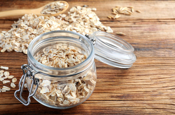 Glass jar with oatmeal on wooden table. Space for text - Φωτογραφία, εικόνα