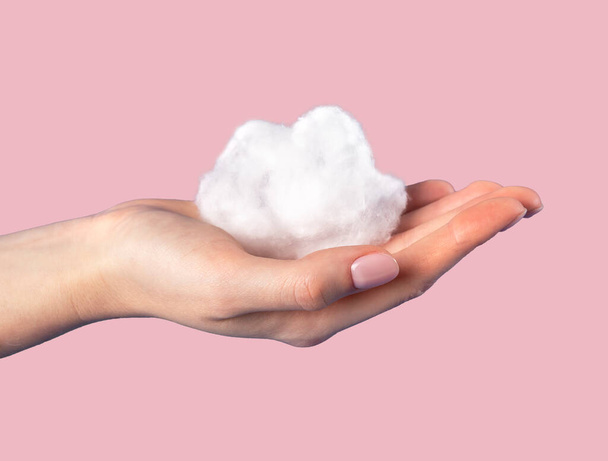 Hand holding cotton cloud at pink background. Dreaming, cloudy weather, climate concept in surrealism style  - Φωτογραφία, εικόνα