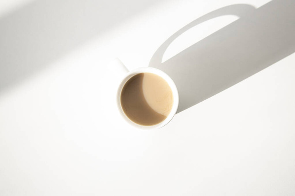Bílý pohár v přirozeném světle na bílém pozadí. Horní pohled rovný  - Fotografie, Obrázek