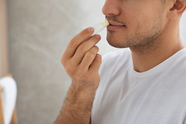 Man die hygiënische lippenbalsem binnen aanbrengt, close-up - Foto, afbeelding
