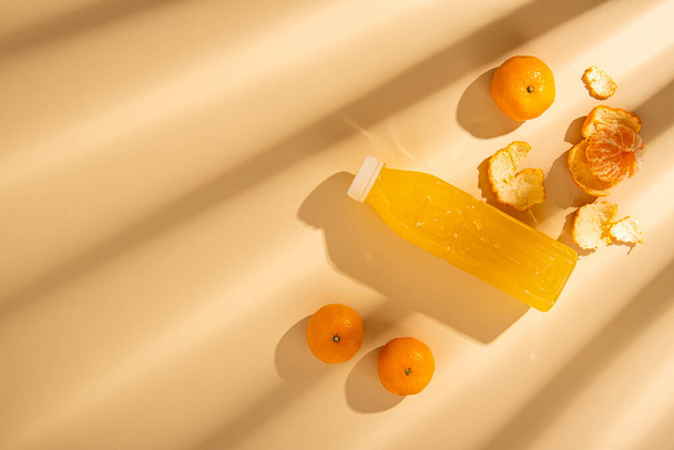 Detox drink in a plastic bottle, tangerines on a beige background. top view, flat lay  - Photo, Image