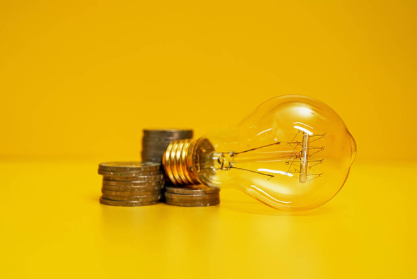 Koncept růstu cen elektřiny. Lampa a mince. - Fotografie, Obrázek
