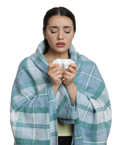 Young woman wrapped in blanket with tissue suffering from cold on white background - Foto, afbeelding