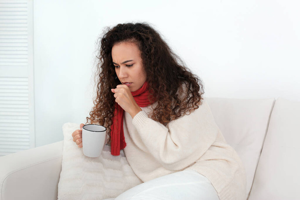 Sick African American woman with cup of hot drink at home - Fotó, kép