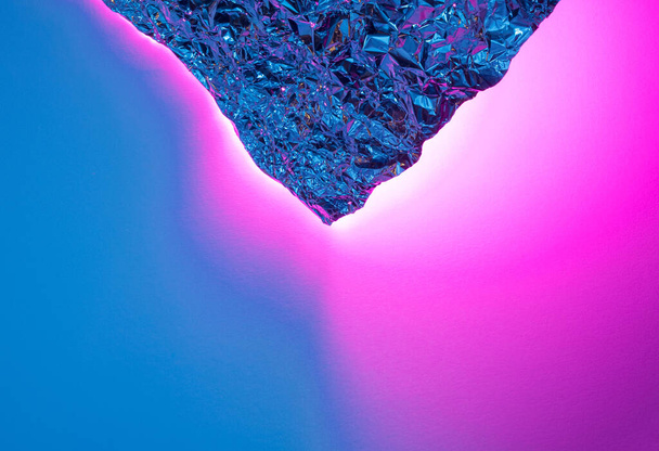 Crumpled aluminum foil with blue and pink light reflections. Futuristic abstract background. - Photo, Image