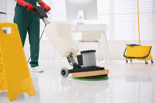 Professional janitor cleaning parquet floor with polishing machine in office, closeup - Фото, зображення