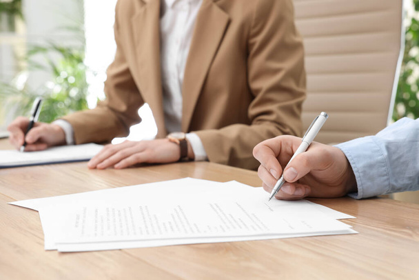 Man signing contract at table in office, closeup. - 写真・画像