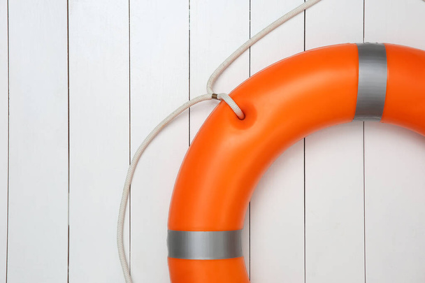 Orange lifebuoy on white wooden background, space for text. Rescue equipment - 写真・画像