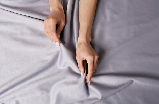 Woman touching soft silver fabric, top view - Foto, Imagen