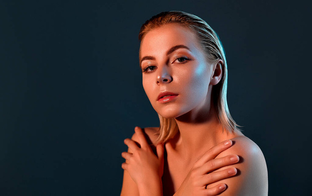 Skin care. A woman with a beautiful face touching the healthy skin of the body. Beautiful girl model with natural makeup. touching glowing moisturized skin on a gray background close up. - Photo, Image