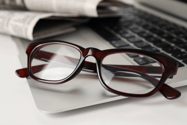 Modern laptop and glasses on white table, closeup - Φωτογραφία, εικόνα