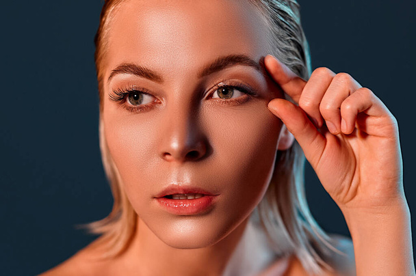 Close-up portrait of nice attractive charming blond nude lady with flawless shine fresh skin showing place near eye lifting botox collagen copy empty blank space isolated on dark gray background - Photo, Image