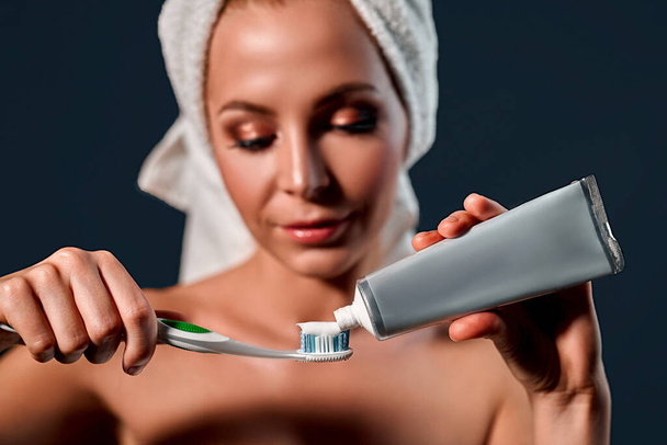 Portret van aantrekkelijke jonge vrouw op grijze achtergrond met tandenborstel en tandpasta. Vrouwen geven om - Foto, afbeelding