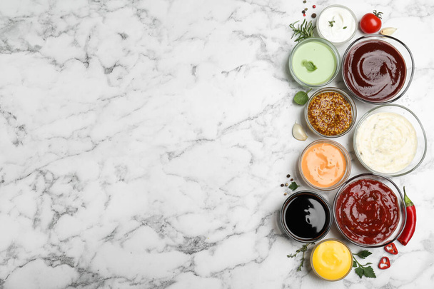 Many different sauces and herbs on white marble table, flat lay. Space for text - Foto, immagini