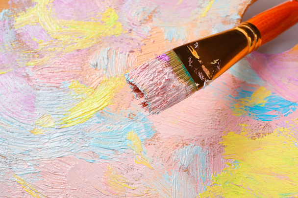 Closeup view of artist's palette with mixed pastel paints and brush as background - Photo, image