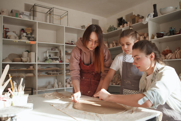 Професійний гончар навчає матір і сина працювати з глиною в художній студії, копіювати простір
 - Фото, зображення