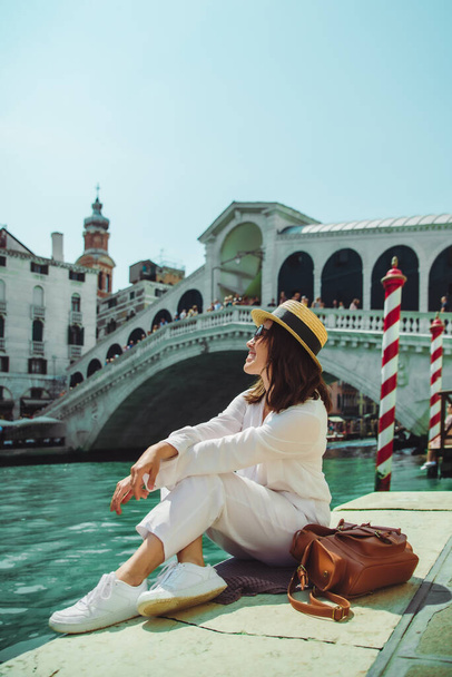 woman sitting near rialto bridge in venice italy looking at grand canal with gondolas summer time copy space - Foto, Imagem