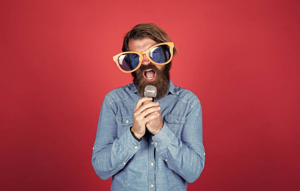 teach me music. hipster man with beard wearing glasses. music concept. have a happy holiday. have fun on party. male singer singing song in microphone. celebrate the anniversary. party goer - Foto, Bild