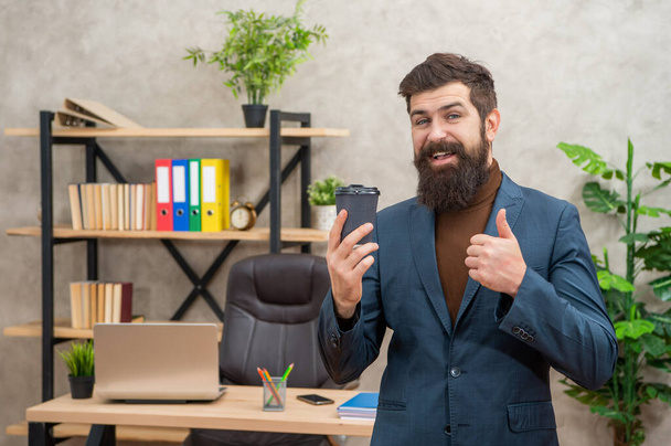 cheerful ceo in businesslike suit hold morning coffee cup at the office showing thumb up, takeaway. - Fotografie, Obrázek