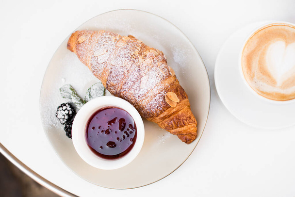 Cup of coffee with heart drawing, croissant and jam on black background. Breakfast on Mothers day, Valentines Day or Womens day. Romantic morning concept. Top view. - 写真・画像