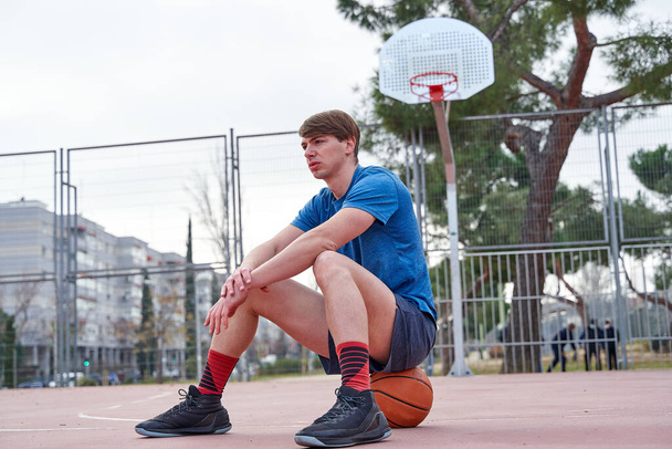 giocatore di basket seduto sulla palla in campo - Foto, immagini