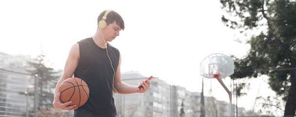 fiatal sportoló egy kosárlabda pálya képzés közben zenét hallgatni. - Fotó, kép