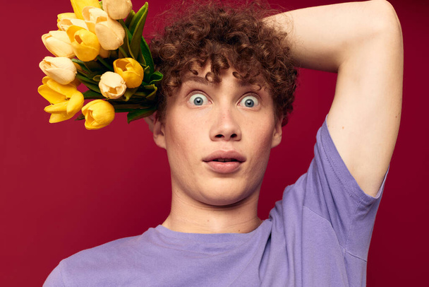 young guy holding a yellow bouquet of flowers purple t-shirts isolated background unaltered - Foto, Imagem