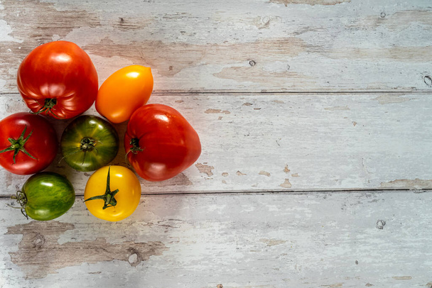 tomates de colores sobre un fondo de madera blanca. plano tiro laico - Foto, Imagen