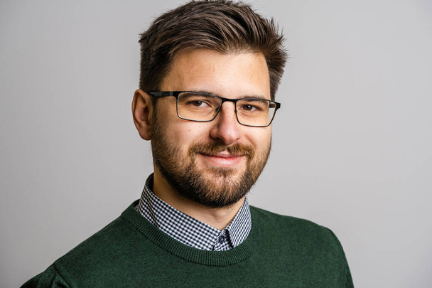 Portrait d'un homme caucasien adulte de 30 ans avec barbe et lunettes regardant vers l'appareil photo en face de fond de mur blanc portant pull jeune homme d'affaires succès concept copier l'espace - Photo, image