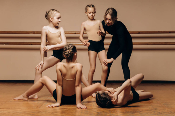 Ganzkörperporträt einer schönen Tanzlehrerin, die eine Gruppe kleiner Mädchen in einem Tanzstudio unterrichtet, einem Raum zum Kopieren.  - Foto, Bild