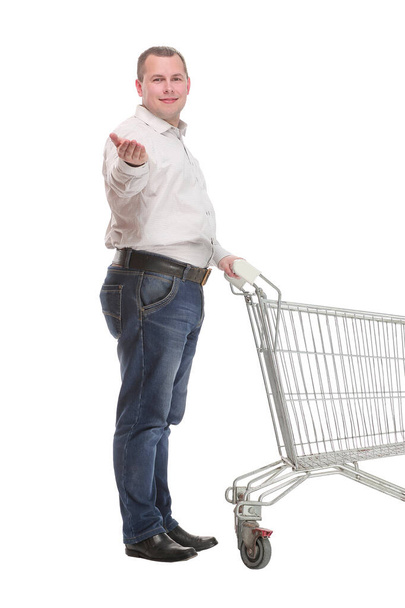 Full length side view of handsome young man standing with shopping trolley and looking at camera - Fotografie, Obrázek
