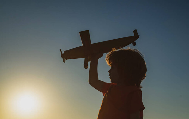 Kids dreams. Boy pilot with toy airplane, silhouette. Child playing outdoors. Happy childhood. Daydreaming. - Foto, Imagem