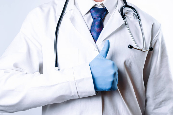 Doctor gesture hands medical background. Happy nurse in blue gloves, hospital uniform, stethoscope isolated on white. Close up, copy space background - 写真・画像
