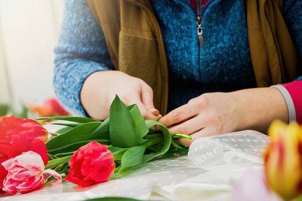 Mujer florista hace ramo de tulipanes frescos. Flores de primavera en floristería. Pequeña empresa para jardineros. Cultivo de plantas en invernadero. - Foto, Imagen