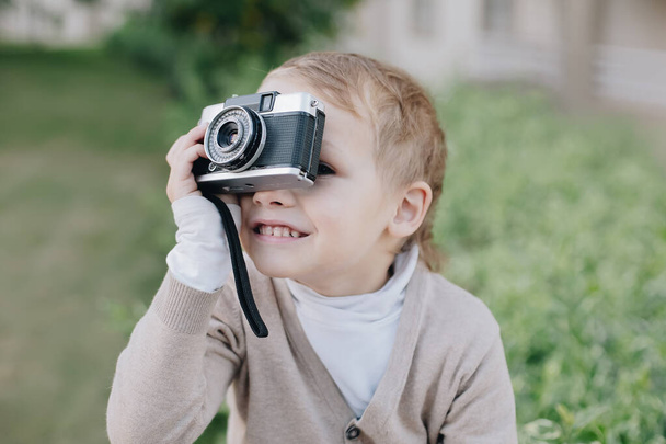 Küçük çocuk fotoğrafçı tebessümü ile analog film retro vintage fotoğraf makinesi açık havada - Fotoğraf, Görsel