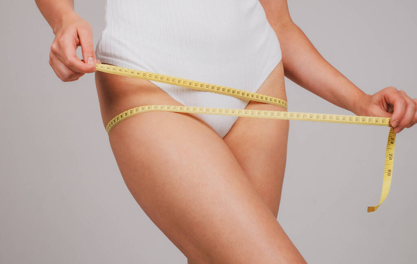 Young slim woman measures her waist by buttocks tape after diet. Concept of weight loss. - Zdjęcie, obraz