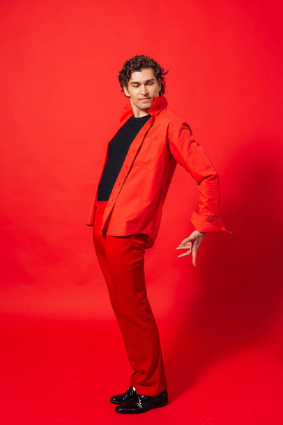 Portrait of a tall handsome man dressed in red shirt posing on the red background. - Photo, image