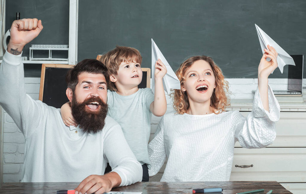 Pupil with paper airplane playing with parents. Family school. Nice family photo of little boy and his Parents. School community partnership. Little ready to study. - Φωτογραφία, εικόνα