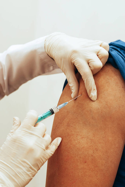 O médico vacina o homem. Close-up foco suave seletivo. Conceito de vacinação mundial - Foto, Imagem