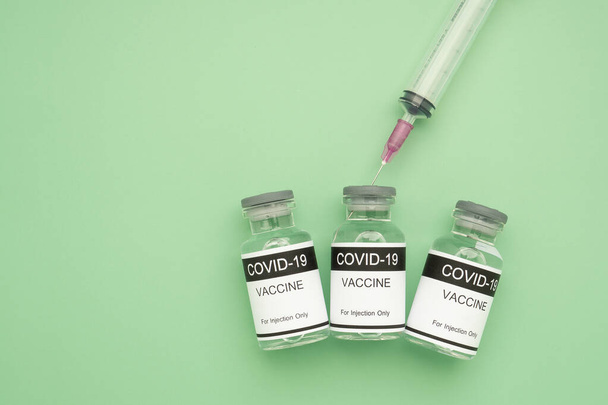 Vakcína COVID-19 ve skleněných lahvičkách s injekční stříkačkou umístěnou na zeleném pozadí. Vakcína pro imunizaci a léčba koronavirovou infekcí. Horní pohled. Koncepce lékařství a zdravotní péče. - Fotografie, Obrázek