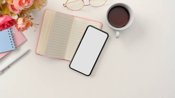 Not defteri, kahve fincanı, gözlük, çiçekler ve akıllı telefon boş ekran maketi olan basit bir çalışma alanı. en üstteki görünüm - Fotoğraf, Görsel