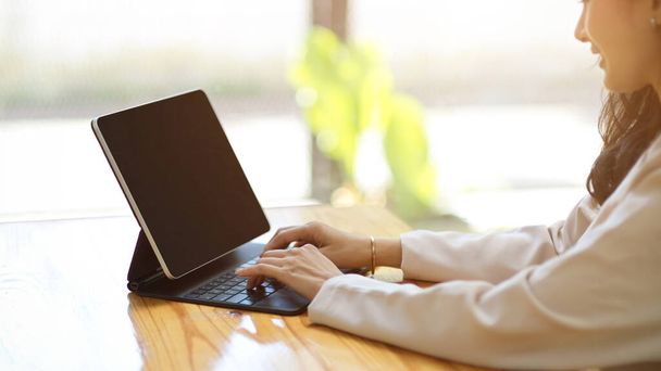Side vie, eine schöne weibliche Eingabe auf der drahtlosen Tablet-Tastatur, Arbeit am Tablet-Computer, Fernarbeit im Café. - Foto, Bild